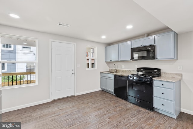 kitchen featuring light wood-style flooring, recessed lighting, visible vents, baseboards, and black appliances