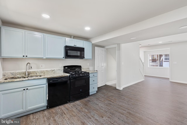 kitchen featuring black appliances, wood finished floors, a sink, and baseboards