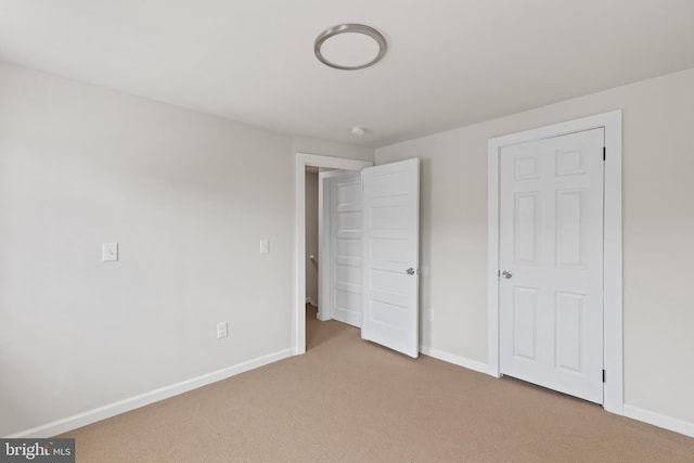 unfurnished bedroom with light carpet and baseboards