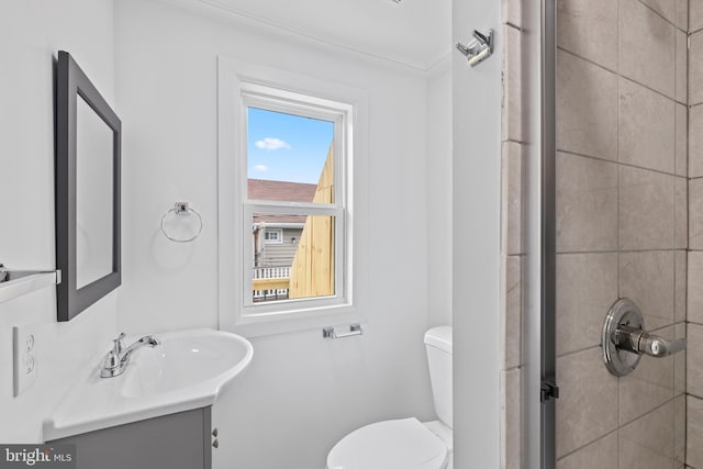 full bath featuring toilet, tiled shower, and vanity