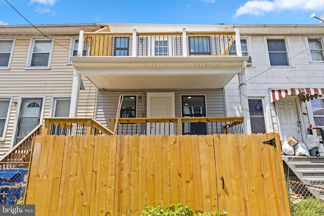 townhome / multi-family property featuring a balcony, covered porch, and a fenced front yard