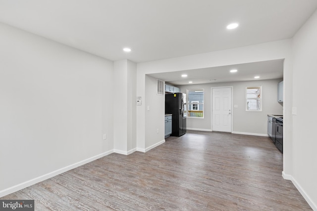 unfurnished living room with recessed lighting, dark wood-style flooring, and baseboards