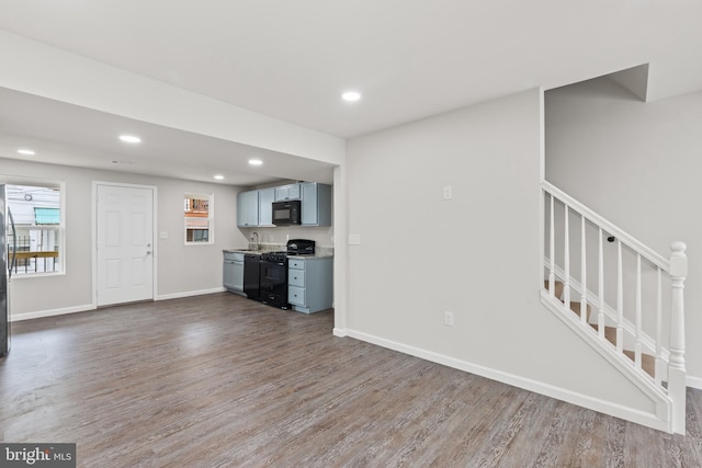 unfurnished living room with stairway, recessed lighting, wood finished floors, and baseboards