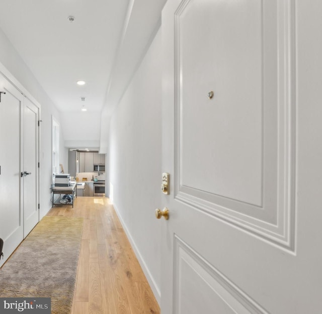 hallway featuring light wood-style flooring and baseboards