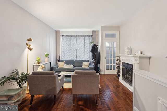 living area featuring a glass covered fireplace, baseboards, and hardwood / wood-style flooring