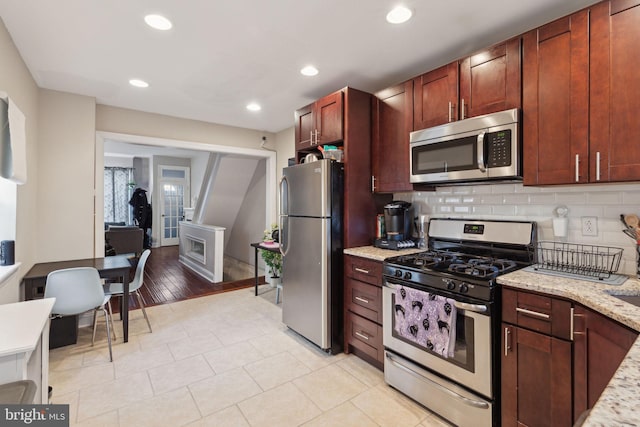 kitchen featuring stainless steel appliances, recessed lighting, light stone counters, and tasteful backsplash