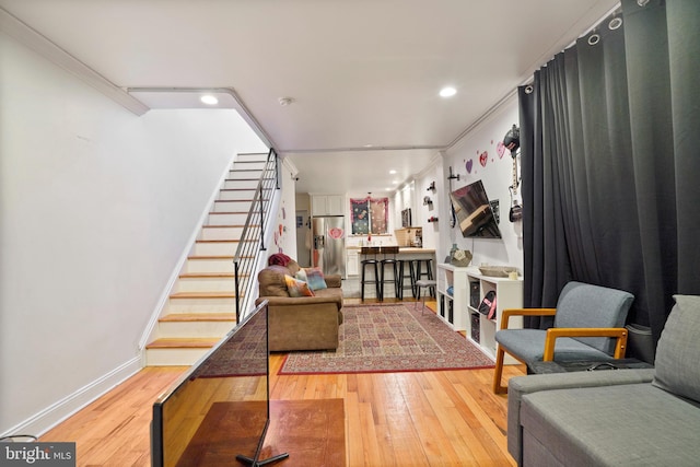 living room featuring recessed lighting, baseboards, light wood finished floors, and stairs