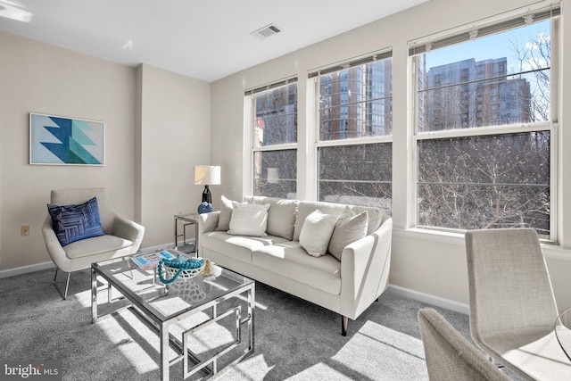 carpeted living room featuring visible vents, baseboards, and a view of city