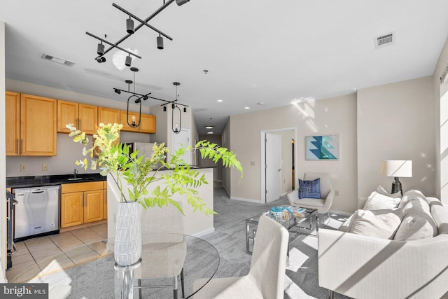 kitchen with visible vents, a sink, stainless steel dishwasher, dark countertops, and open floor plan