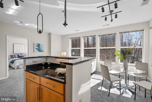 kitchen featuring visible vents, carpet floors, a kitchen island, and brown cabinets