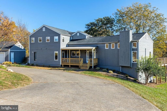 view of front of home featuring covered porch, a shingled roof, and a chimney