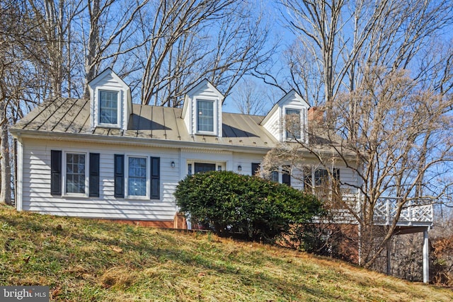 cape cod home with metal roof and a front lawn