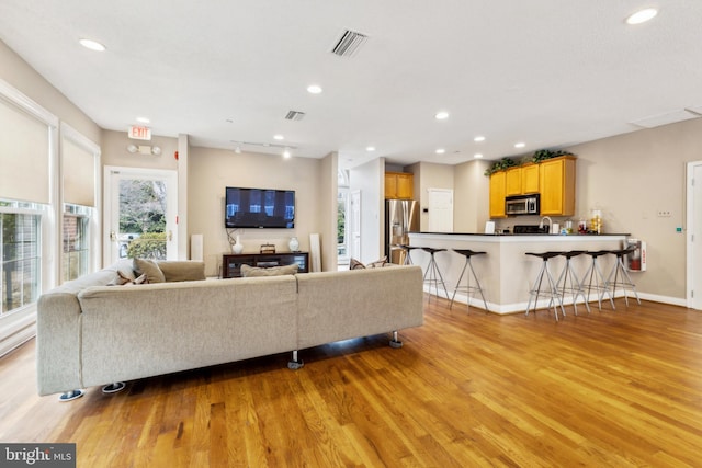 living area featuring recessed lighting, visible vents, baseboards, light wood finished floors, and rail lighting