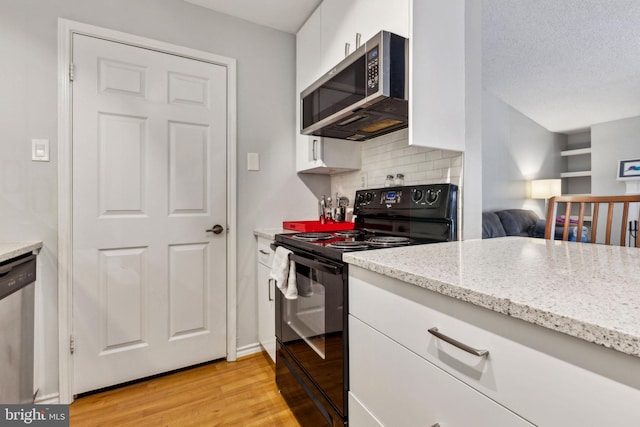 kitchen with light stone counters, light wood-style flooring, decorative backsplash, appliances with stainless steel finishes, and white cabinets