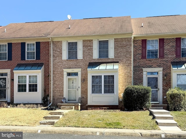 multi unit property featuring brick siding and a front lawn