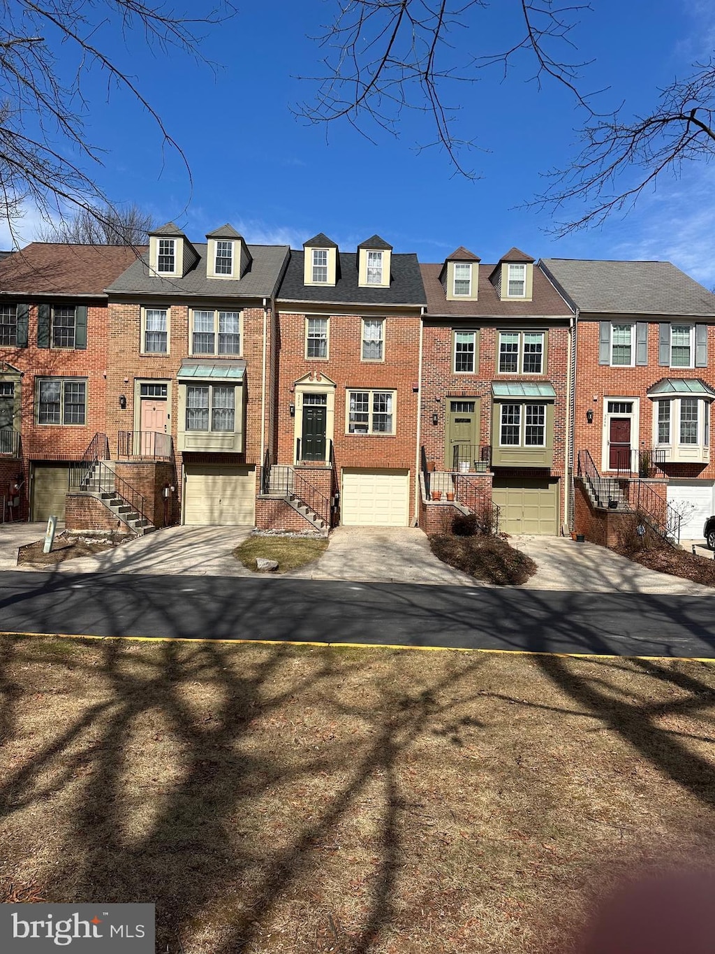 view of property with a garage, concrete driveway, brick siding, and a residential view