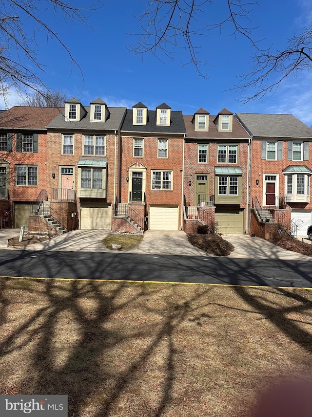 view of property with a garage, concrete driveway, brick siding, and a residential view