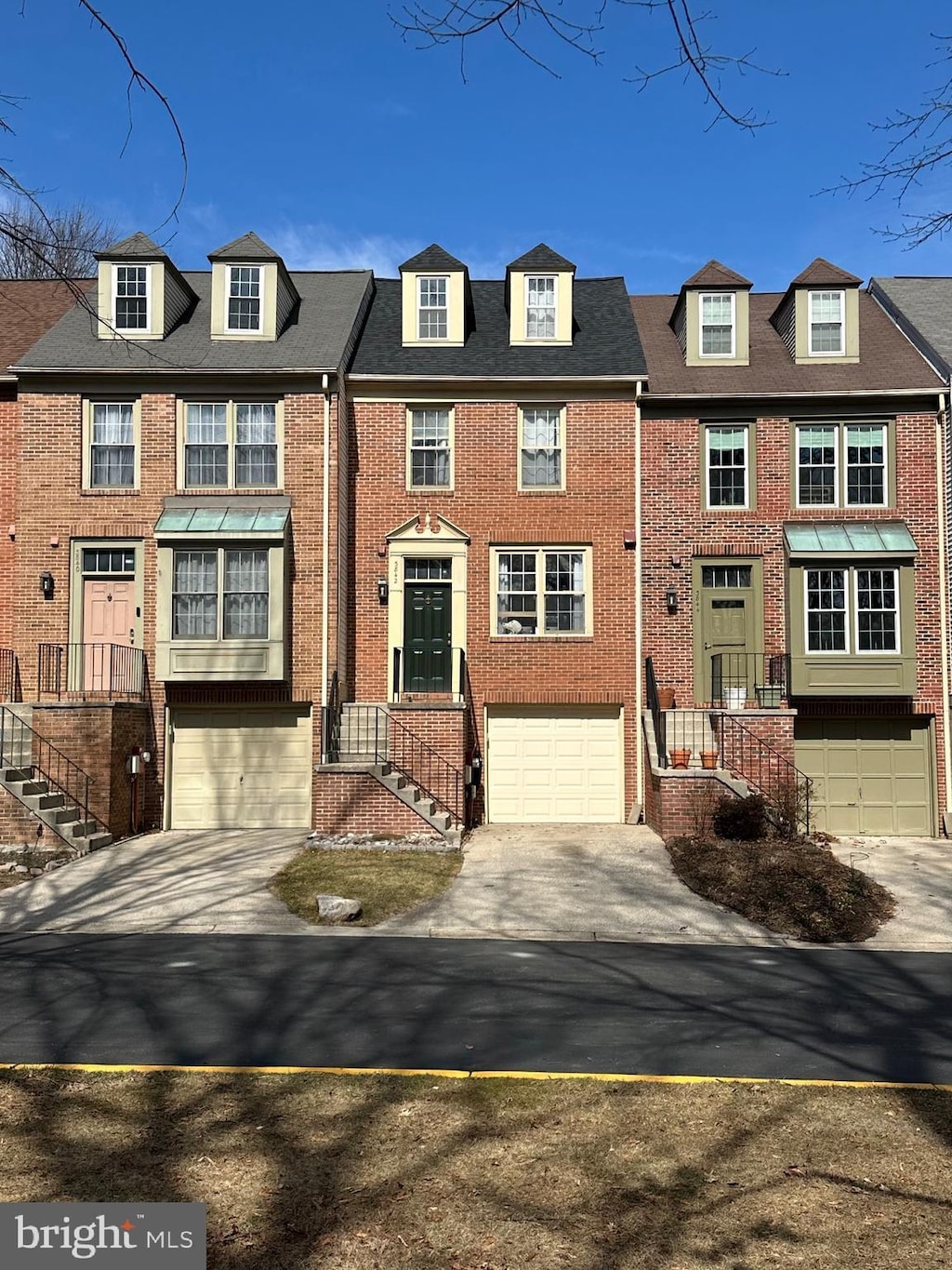 townhome / multi-family property featuring a garage, concrete driveway, and brick siding