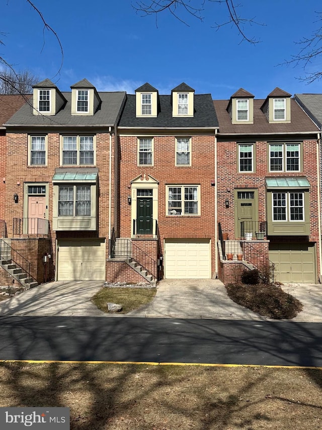 townhome / multi-family property featuring a garage, concrete driveway, and brick siding