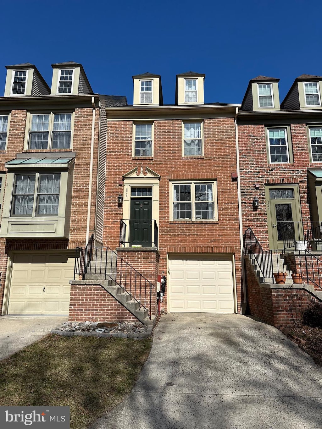 townhome / multi-family property featuring an attached garage, concrete driveway, and brick siding