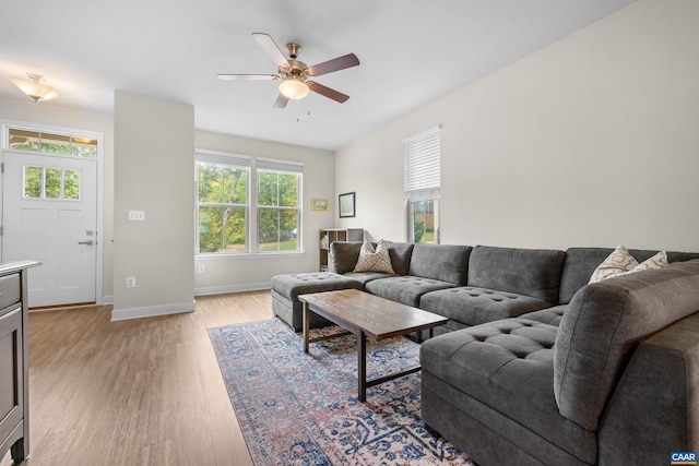 living area with light wood-style flooring, baseboards, and ceiling fan