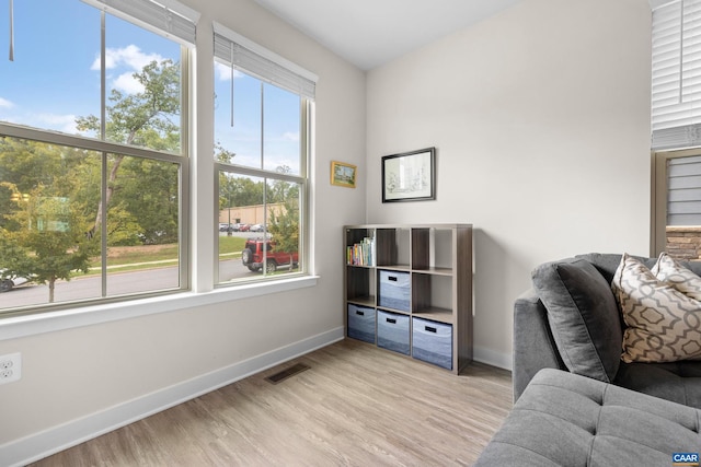 sitting room featuring light wood-style flooring, visible vents, and baseboards