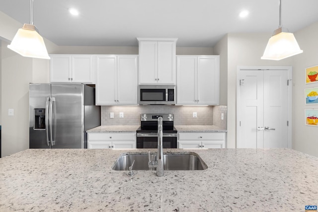 kitchen with white cabinets, stainless steel appliances, backsplash, and decorative light fixtures