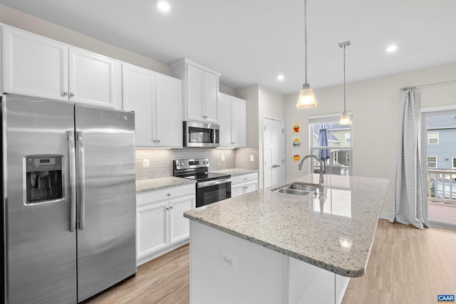 kitchen featuring stainless steel appliances, backsplash, a kitchen island with sink, white cabinetry, and a sink