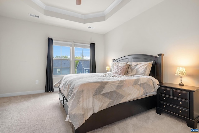 bedroom with light colored carpet, a tray ceiling, visible vents, and baseboards