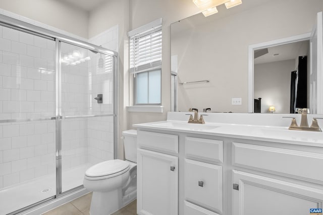 bathroom featuring toilet, a sink, a shower stall, tile patterned floors, and double vanity