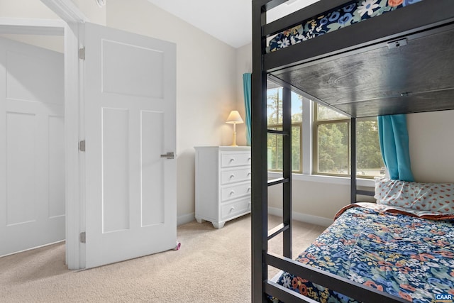 bedroom with baseboards, vaulted ceiling, and light colored carpet