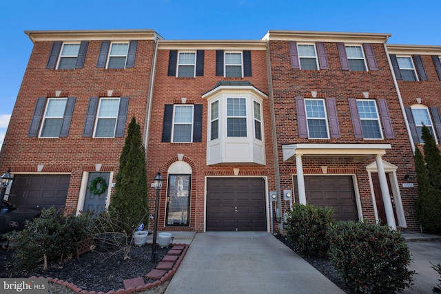 townhome / multi-family property featuring a garage, brick siding, and driveway