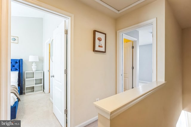 corridor featuring baseboards and light colored carpet