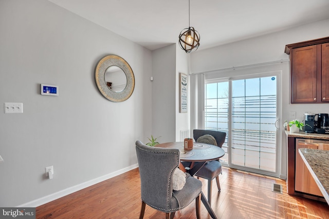 dining space featuring baseboards, visible vents, and light wood finished floors