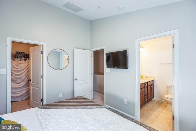 bedroom with a spacious closet, visible vents, connected bathroom, and light tile patterned flooring