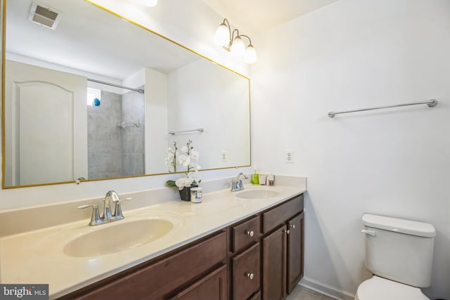 bathroom featuring toilet, double vanity, visible vents, and a sink