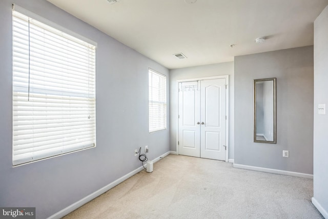 unfurnished bedroom with carpet, a closet, visible vents, and baseboards