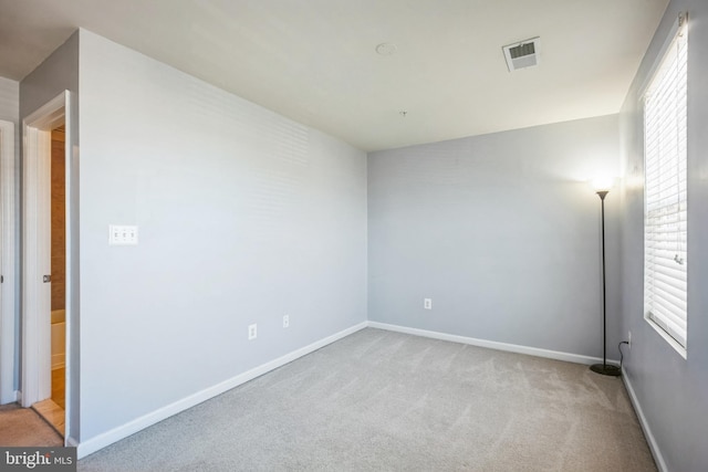 unfurnished room with light carpet, visible vents, and baseboards