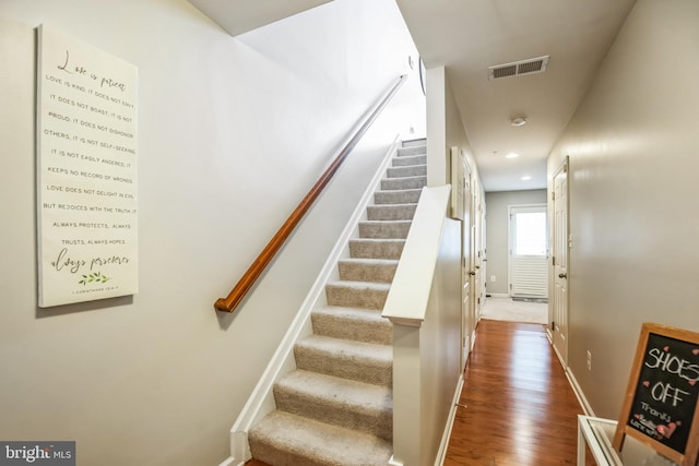 stairway with recessed lighting, visible vents, baseboards, and wood finished floors