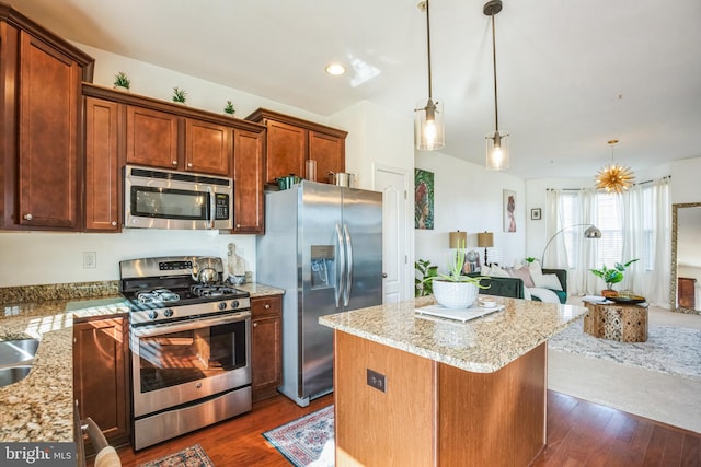 kitchen featuring light stone countertops, a kitchen island, stainless steel appliances, and dark wood-style flooring