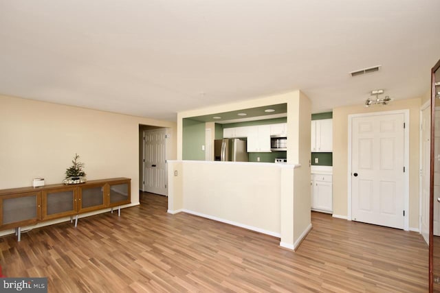 interior space with light wood-type flooring, visible vents, and baseboards