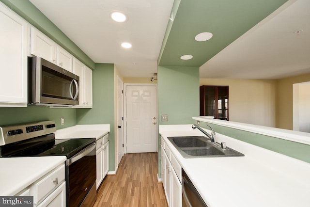 kitchen featuring appliances with stainless steel finishes, white cabinets, a sink, and light countertops