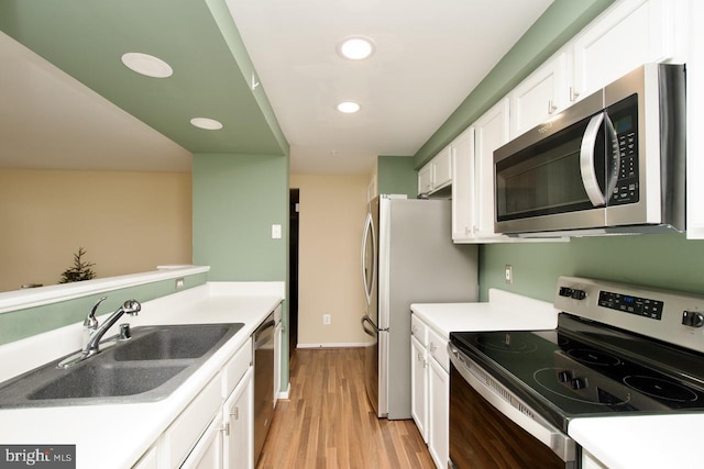 kitchen with light wood finished floors, white cabinetry, appliances with stainless steel finishes, and a sink