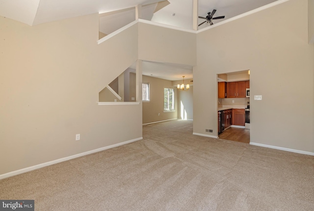 unfurnished living room with light carpet, baseboards, and ceiling fan with notable chandelier