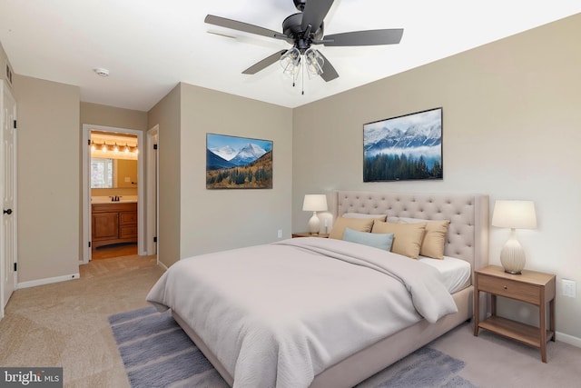 bedroom featuring light carpet, a sink, ensuite bath, and baseboards