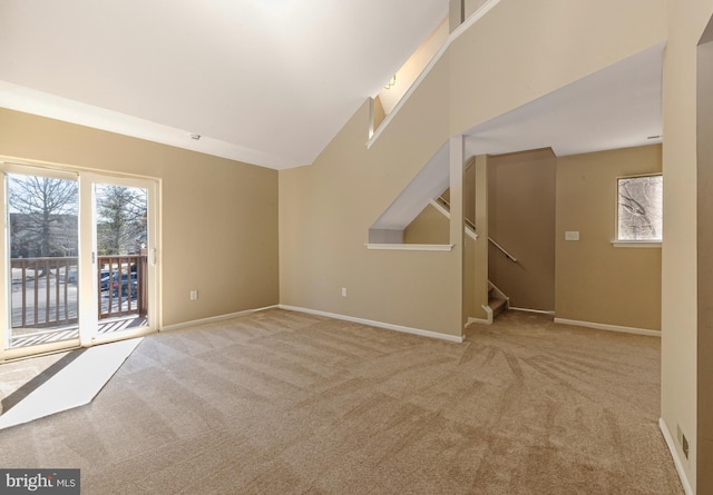 carpeted spare room featuring stairway, a towering ceiling, and baseboards