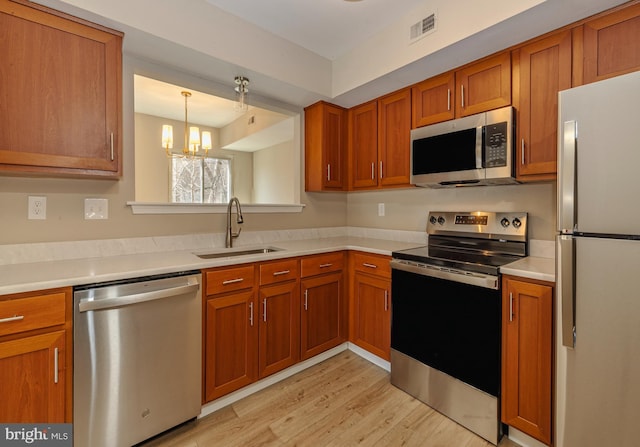 kitchen featuring visible vents, brown cabinets, stainless steel appliances, light countertops, and a sink