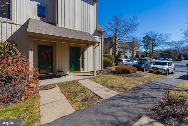 property entrance featuring a shingled roof and board and batten siding