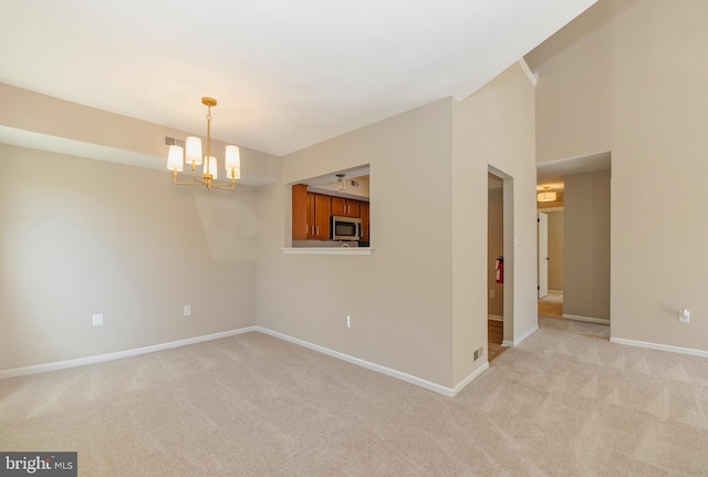 unfurnished room featuring light carpet, a notable chandelier, and baseboards