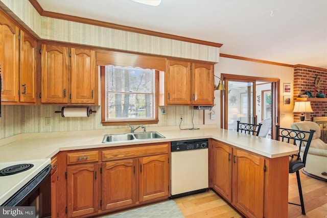 kitchen featuring a breakfast bar area, a peninsula, white dishwasher, light countertops, and a sink